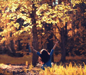 happy girl surrounded by fall colored trees