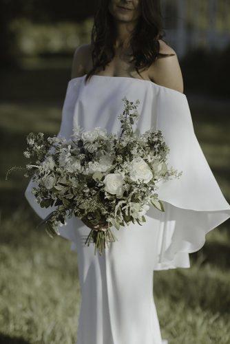 sage green wedding bouquet with white flowers and greenery in hand of the bride in original bridal dress jenny demarco weddings