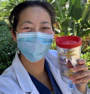 Healthcare worker in coat and mask with a Tervis tumbler