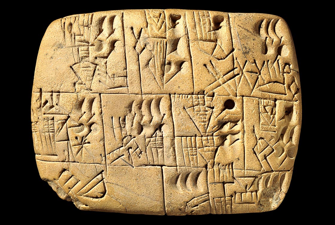 A sandy brown clay tablet inscribed all over with cuneiform.