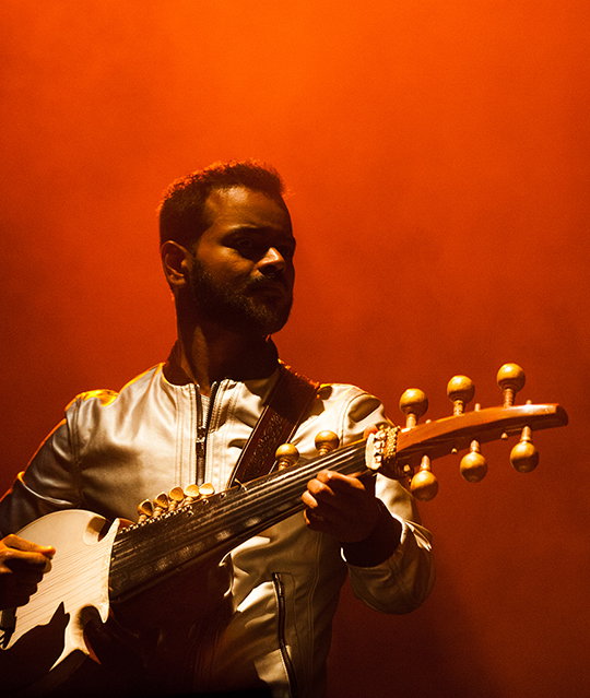 A photo of a man playing an instrument with an orange light.