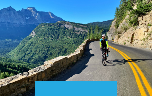 Trek Travel guide cycling on a mountainside road with view of mountains and forests below and in the distance