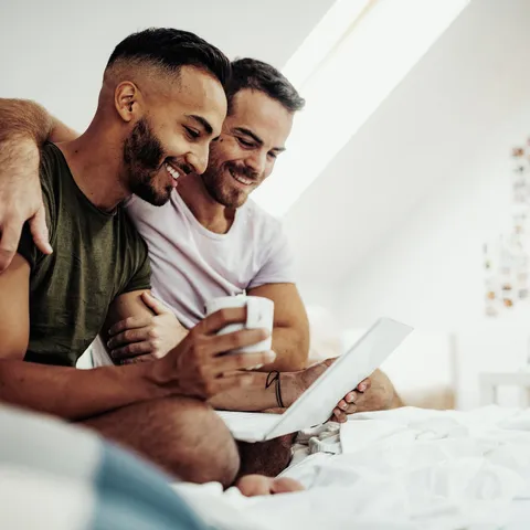 A couple sitting in bed looking at a computer.