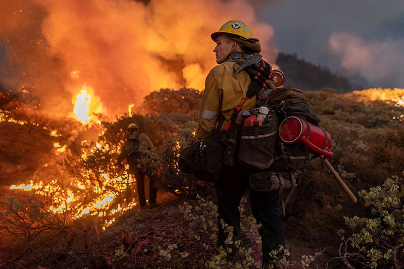 Firefighters laden with equipment approach part of a forest fire near Caldor, California.