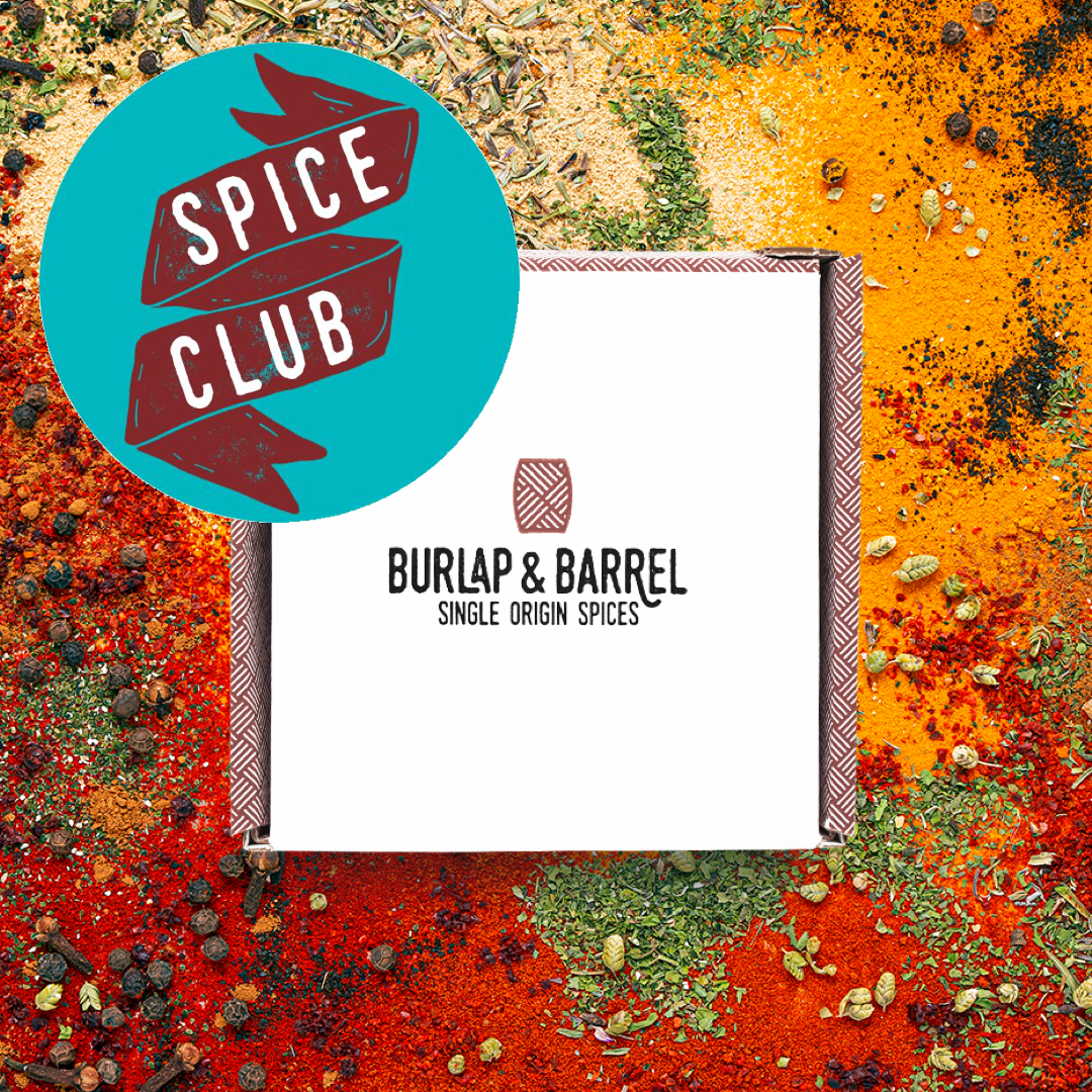 White Burlap & Barrel box on top of a brightly colored array of spices with a teal sticker that says, "Spice Club"