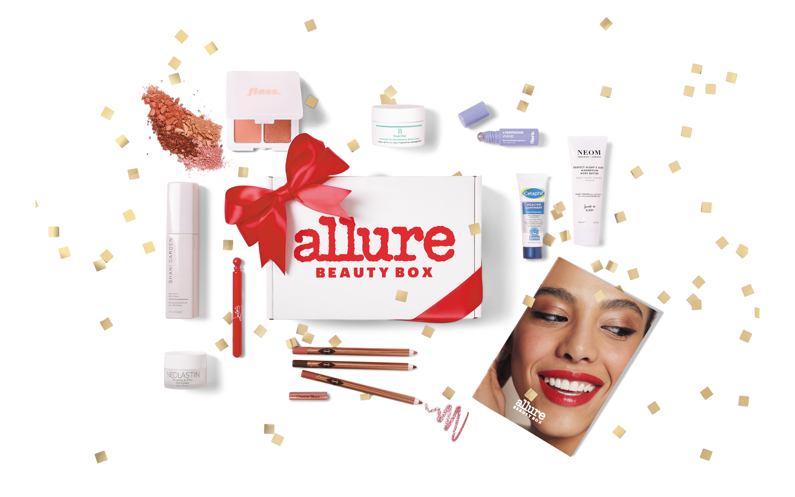 All the items that come in the December Allure Beauty Box laid out against a white background with gold confetti