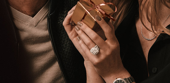 Man and woman smiling at each other while woman holds a small gift box