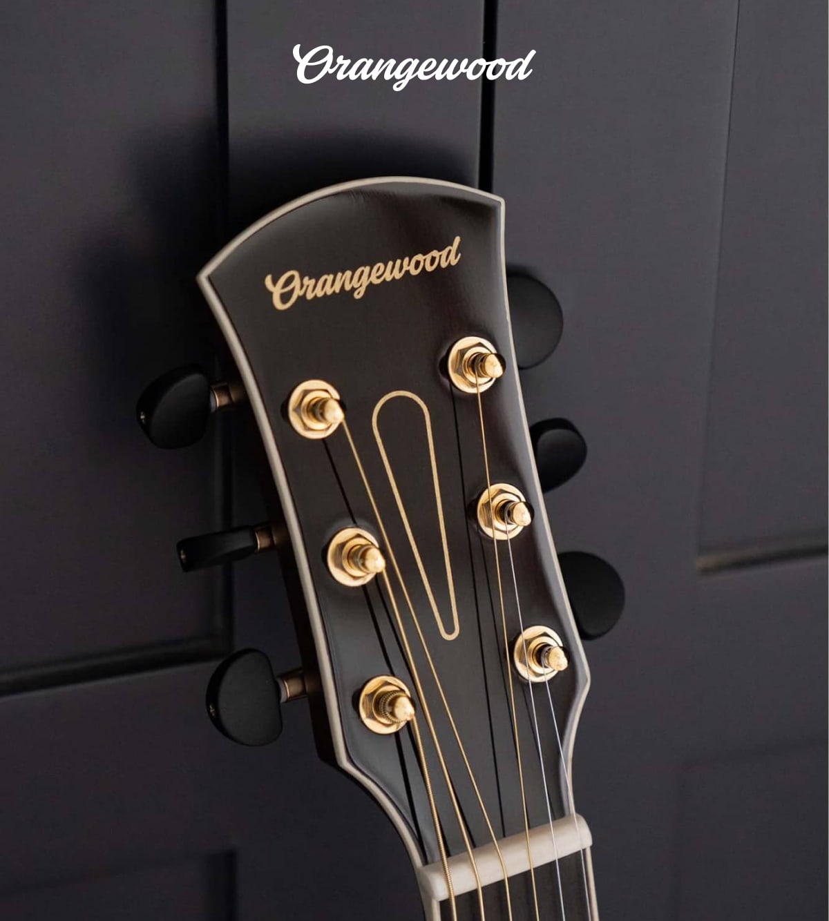 Closeup of orangewood headstock with new logo in a script typeface
