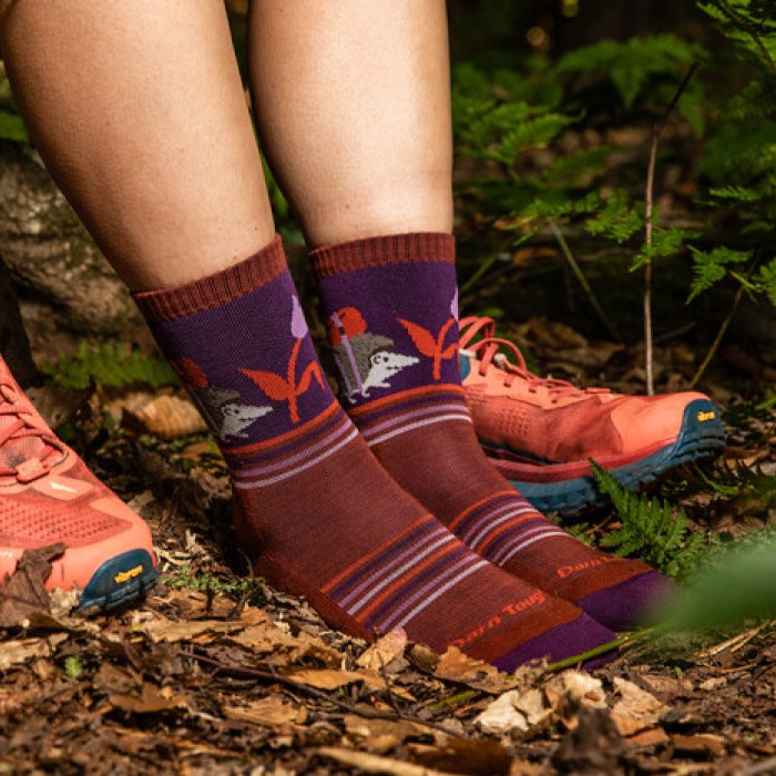 A hiker's feet styling the Critter Club spring hiking socks, featuring an adorable backpacking hedgehog and tulip design.