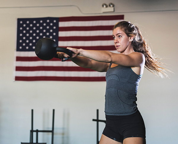 Person doing kettlebell swings in front of an American flag