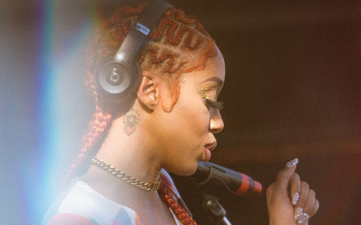 Side profile of Kitty Ca$h with orange braids and black beat by Dre head phones on her head with her ear uncovered