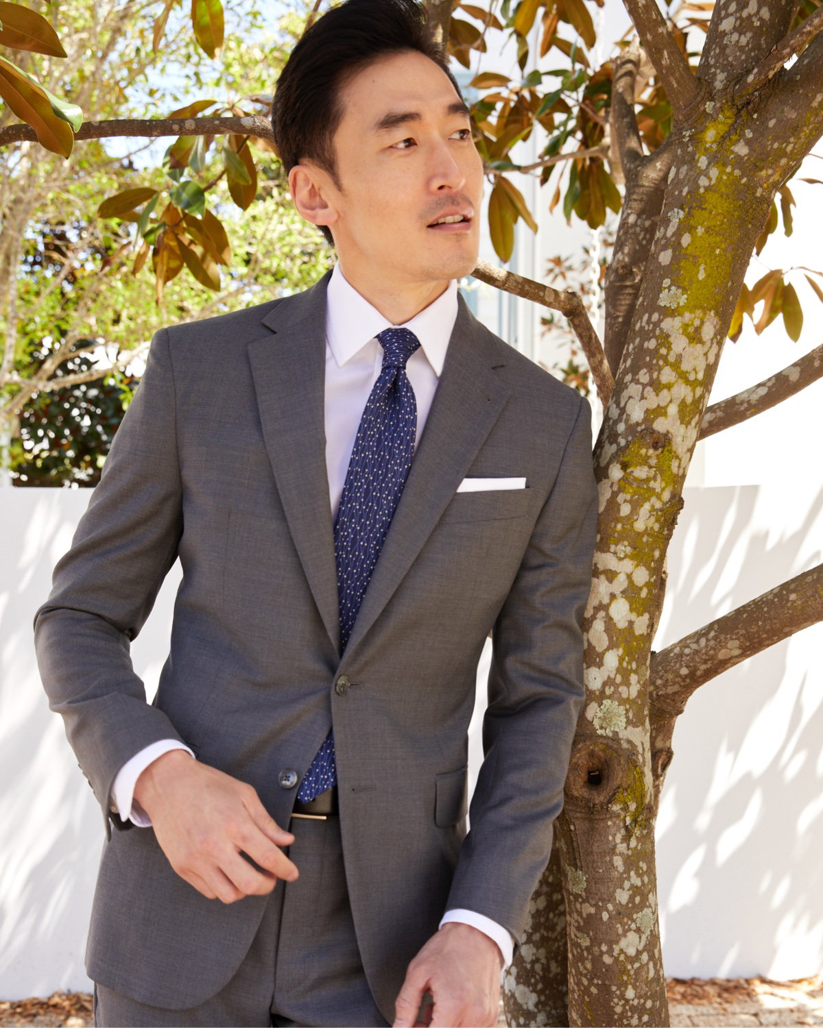 Man in gray shirt leaning against tree