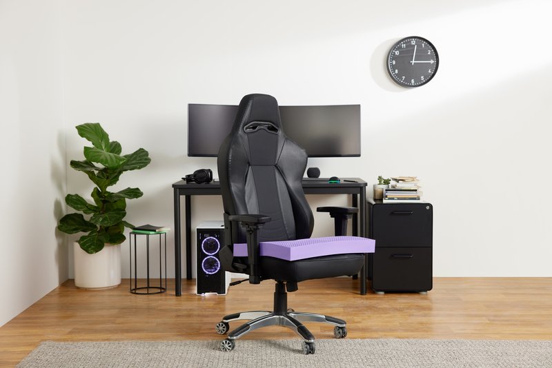 A Purple seat cushion set on an office chair.