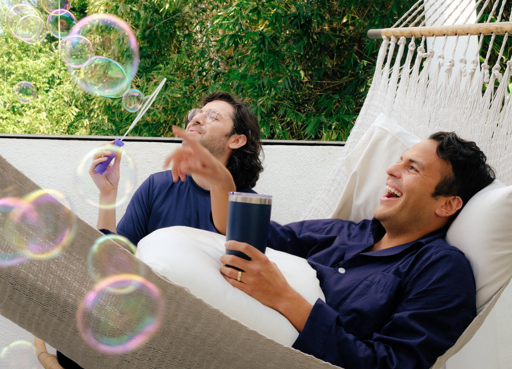 Two men blowing bubbles and lying in a hammock with Slumber Cloud pillows