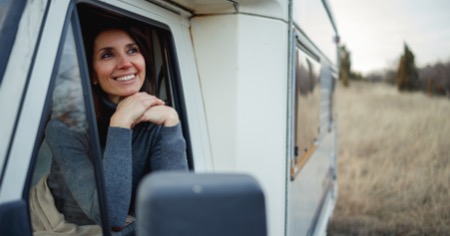 Eine Frau sitzt im Wohnmobil und lächelt, weil ihr Wohnmobil mit einem Feuerlöscher ausgestattet und somit brandschutzsicher ist.