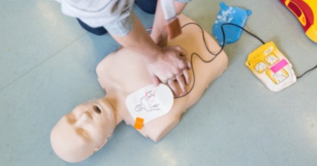 Ein Ersthelfer übt die Herzdruckmassage an einer Übungspuppe