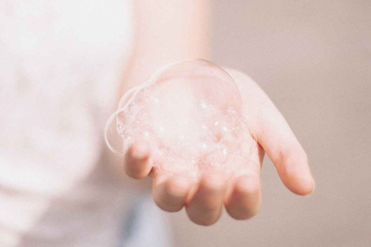 An open hand holding a group of soap bubbles.