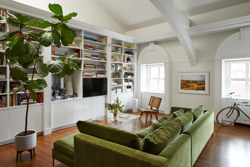 a living room with a large green sofa and bookshelves