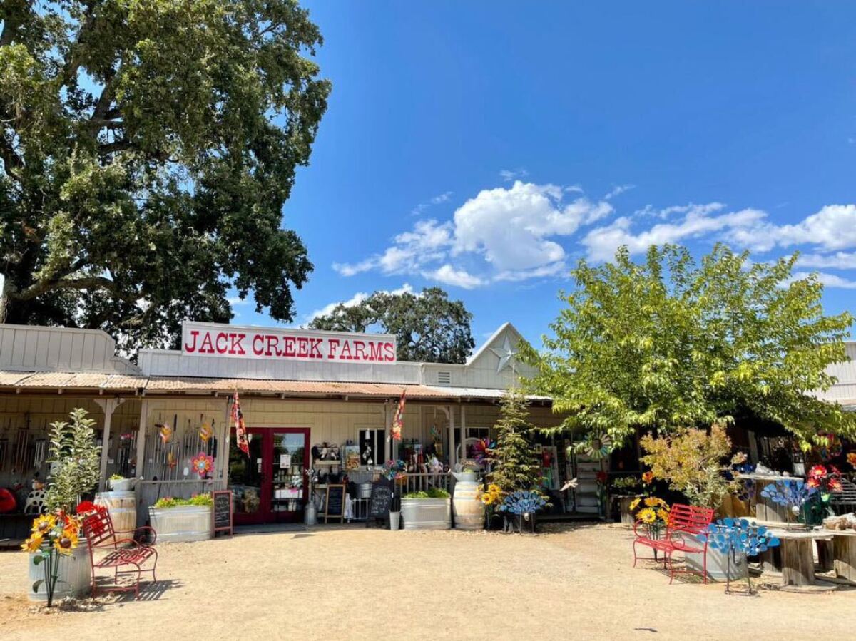 Exterior of a colorful country story, with a sign that says "Jack Creek Farms" in red over the front door.