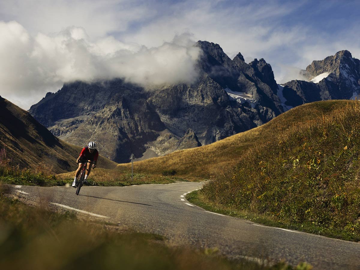 Cyclist wearing helmet on paved road with mountains in background