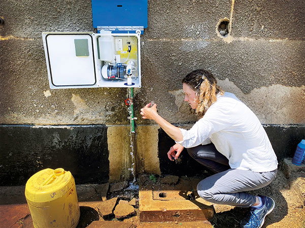 Amy Pickering crouches under a tap examining a small vial of drinking water in Dhaka
