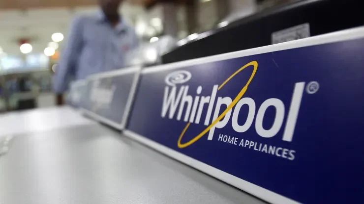 An employee stands next to a Whirlpool washing machine inside a home appliances showroom in New Delhi.