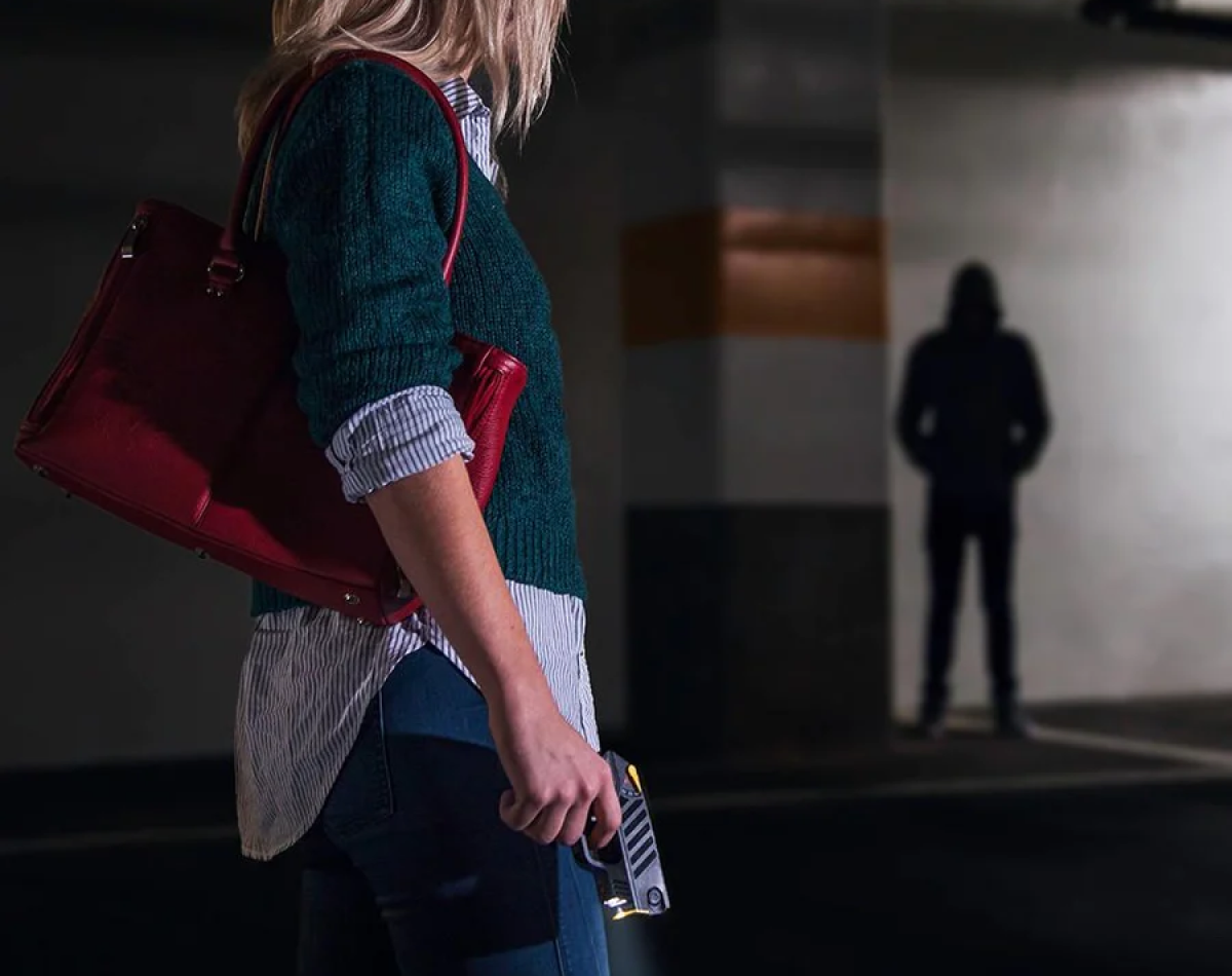 woman carrying taser gun in dark dark parking garage