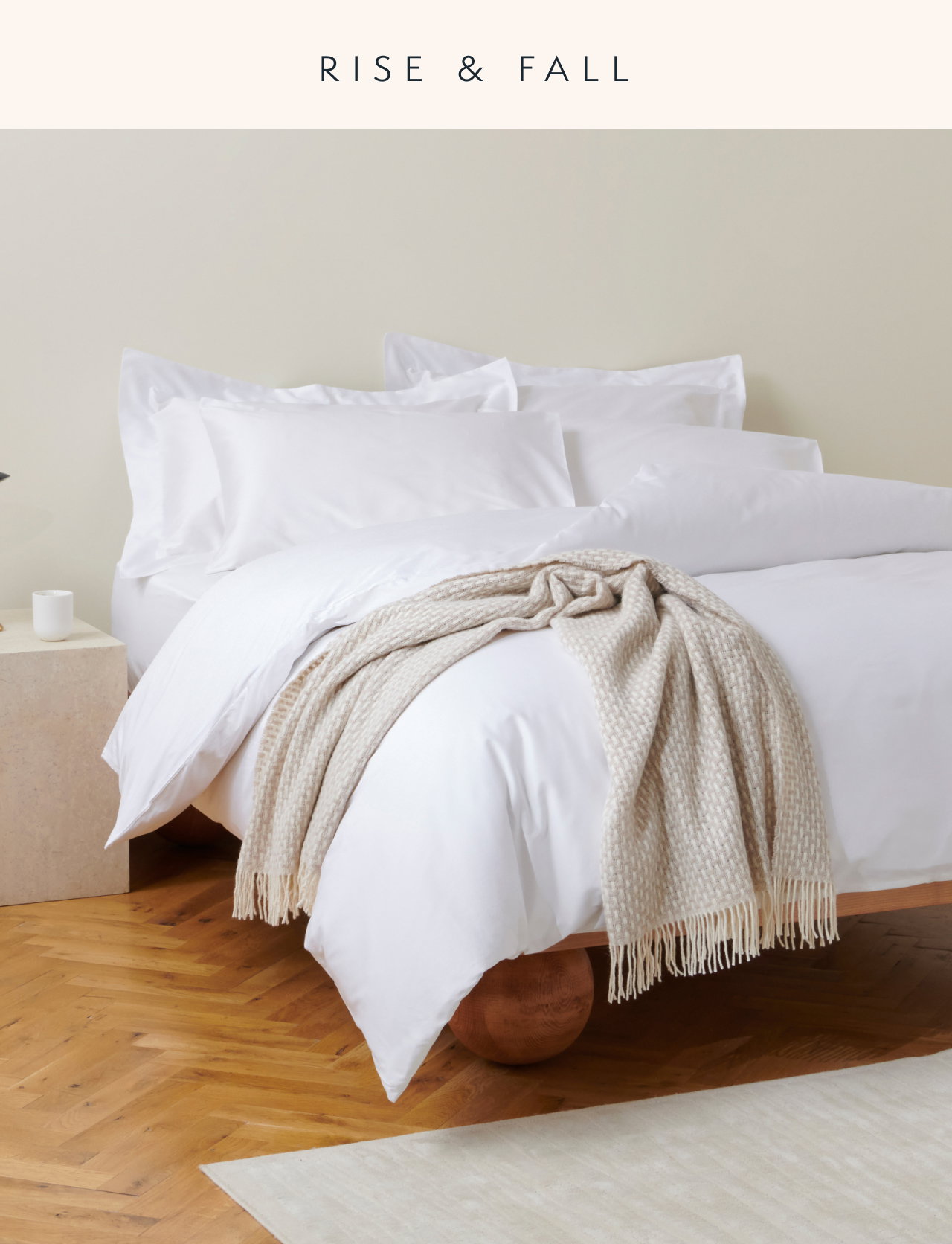 Image of a bed made with soft white bedding, and a woven throw draped over the corner