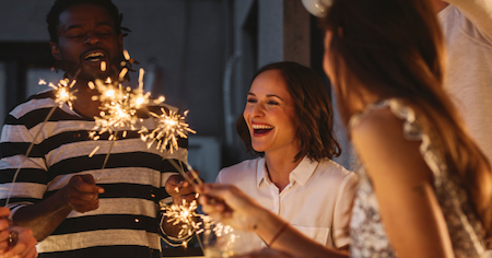 Eine Gruppe von Menschen feiert  mit Wunderkerzen in der Hand Silvester