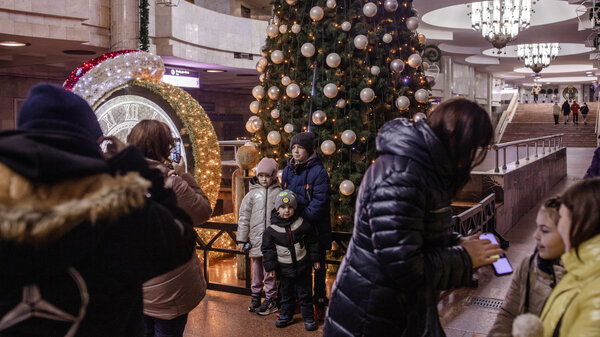 Children pose for photos in front of a Christmas tree and other holiday decorations in a metro station in Kharkiv, Ukraine, on Dec. 11.