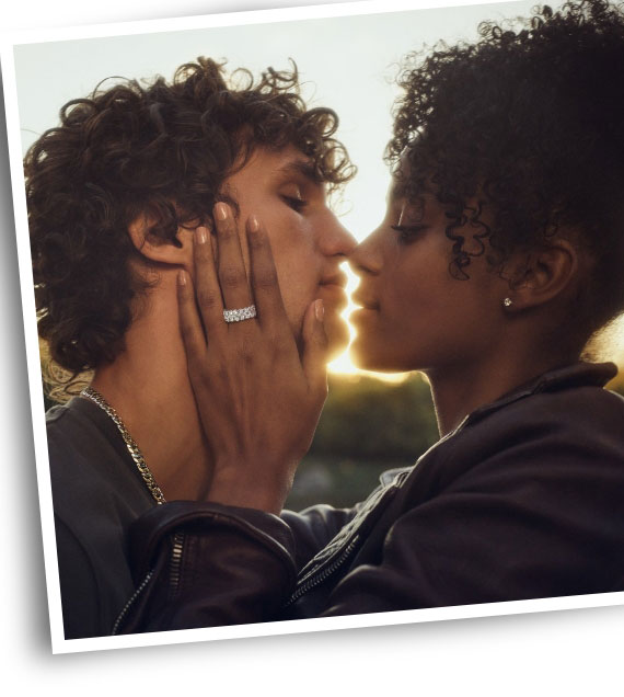 Couple facing each other with sunset in background. Woman wearing KAY ring.