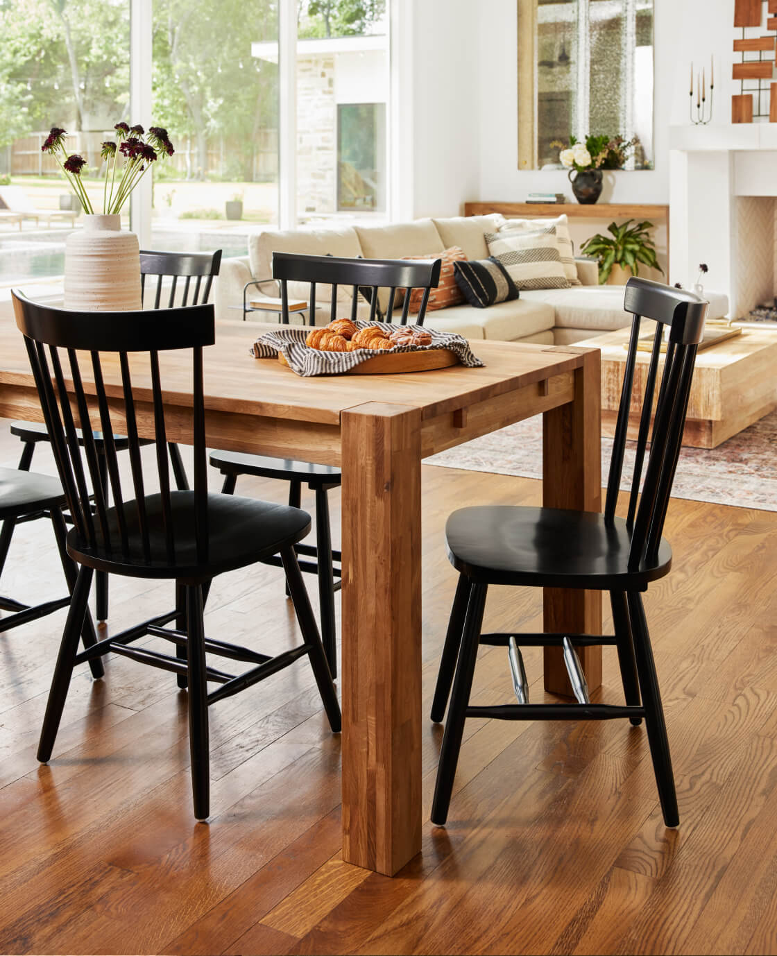 Lifestyle shot of the Harvest Dining Table with Lydia Side Chairs,  view of living room in the back.