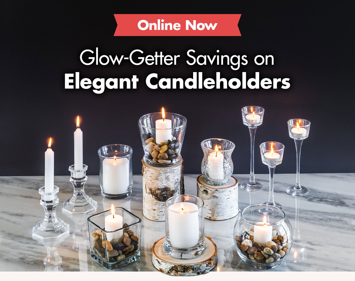 Display of candles and glass candleholders in a variety of shapes and sizes styled on a marble countertop with birch rounds and stones