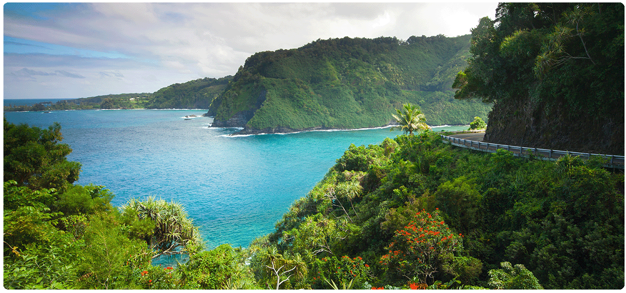 Coast of Hawaii green lush mountains and turquoise inlet. View cruises to Hawaii.