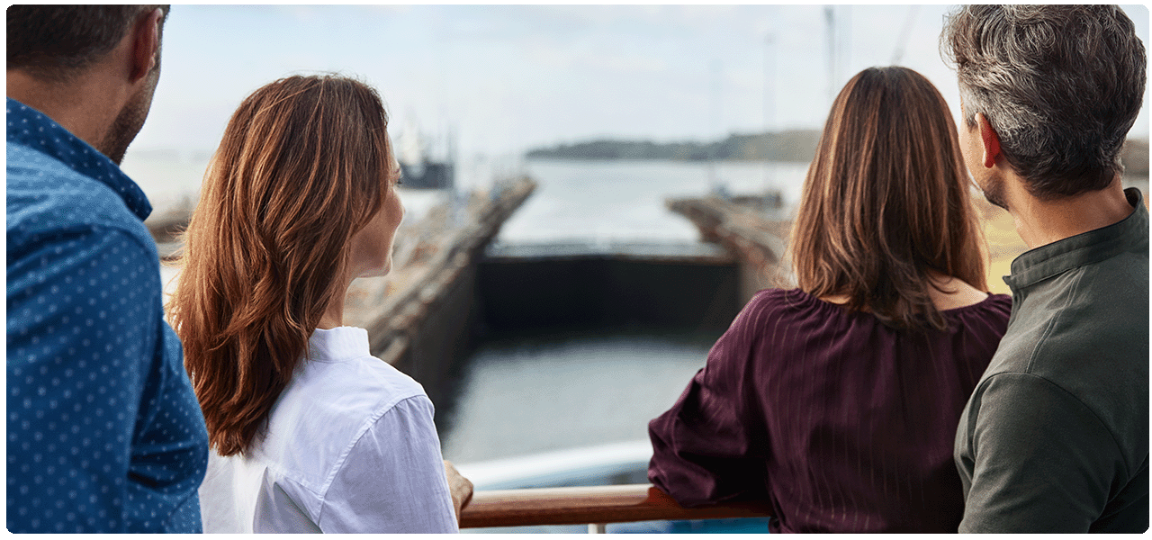 Two couples on deck watching ship going through Panama Canal locke. View cruises to the Panama Canal.
