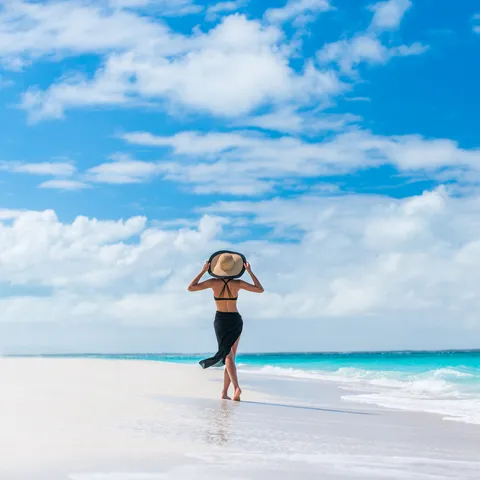 Luxury travel woman in black beachwear sarong walk