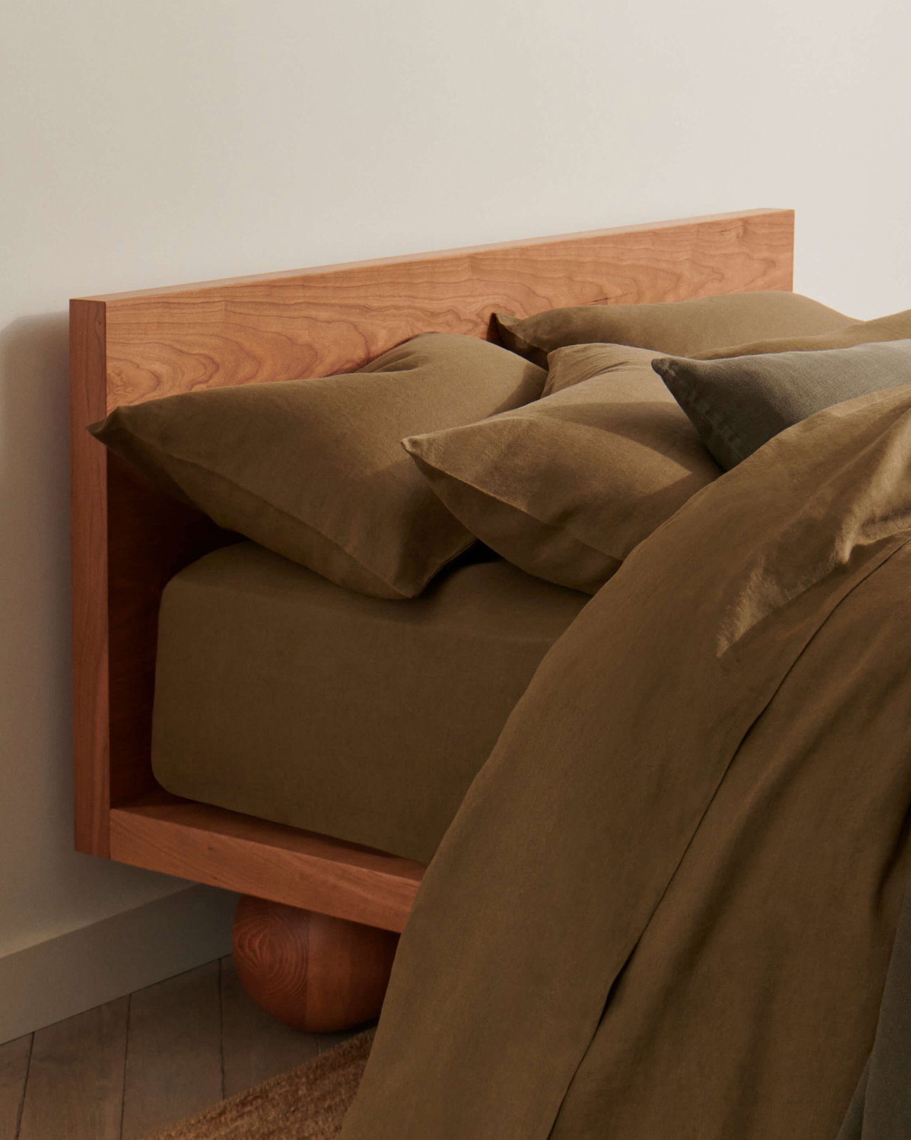 Picture of a bed made up in Rise & Fall linen bedding in olive