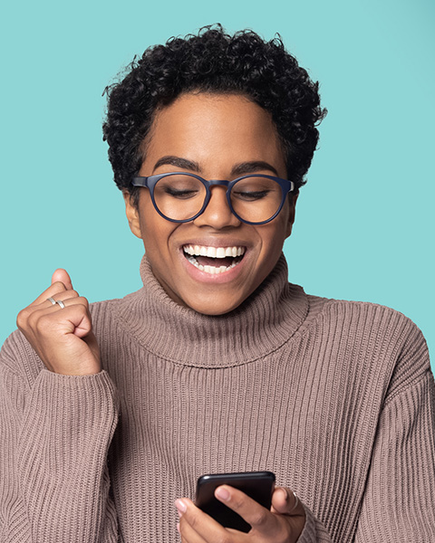 photo of a woman smiling and looking at her mobile phone