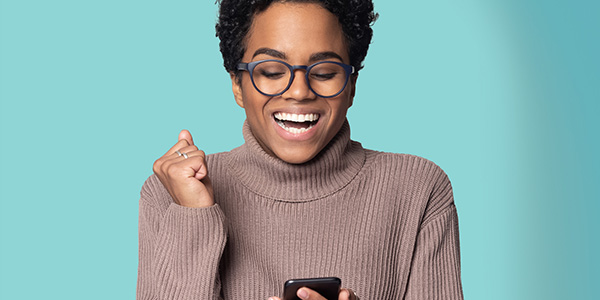 photo of a woman smiling and looking at her mobile phone