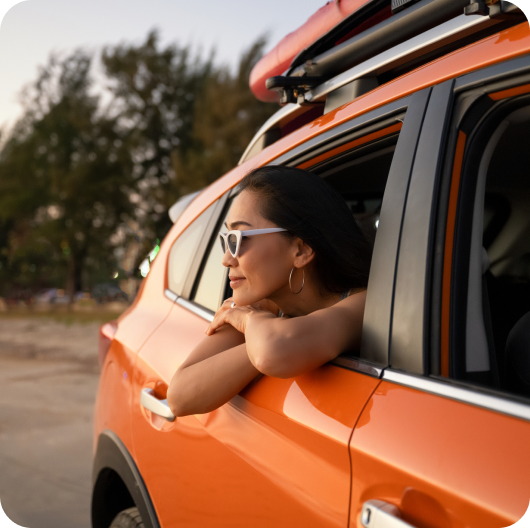A person sticking their head out a window in an orange vehicle linking to 15% off road tripping page