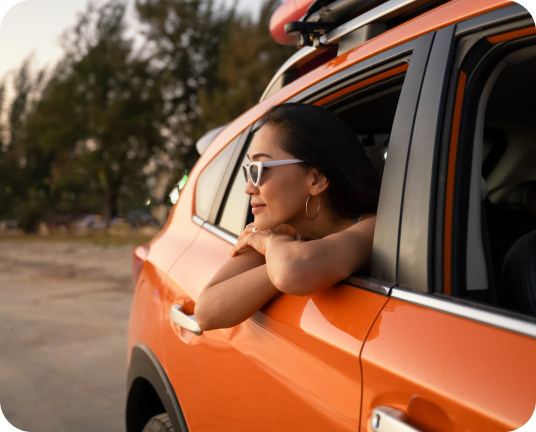A person sticking their head out a window in an orange vehicle linking to 15% off road tripping page