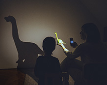 a mother and sun shining a flashlight on a wall