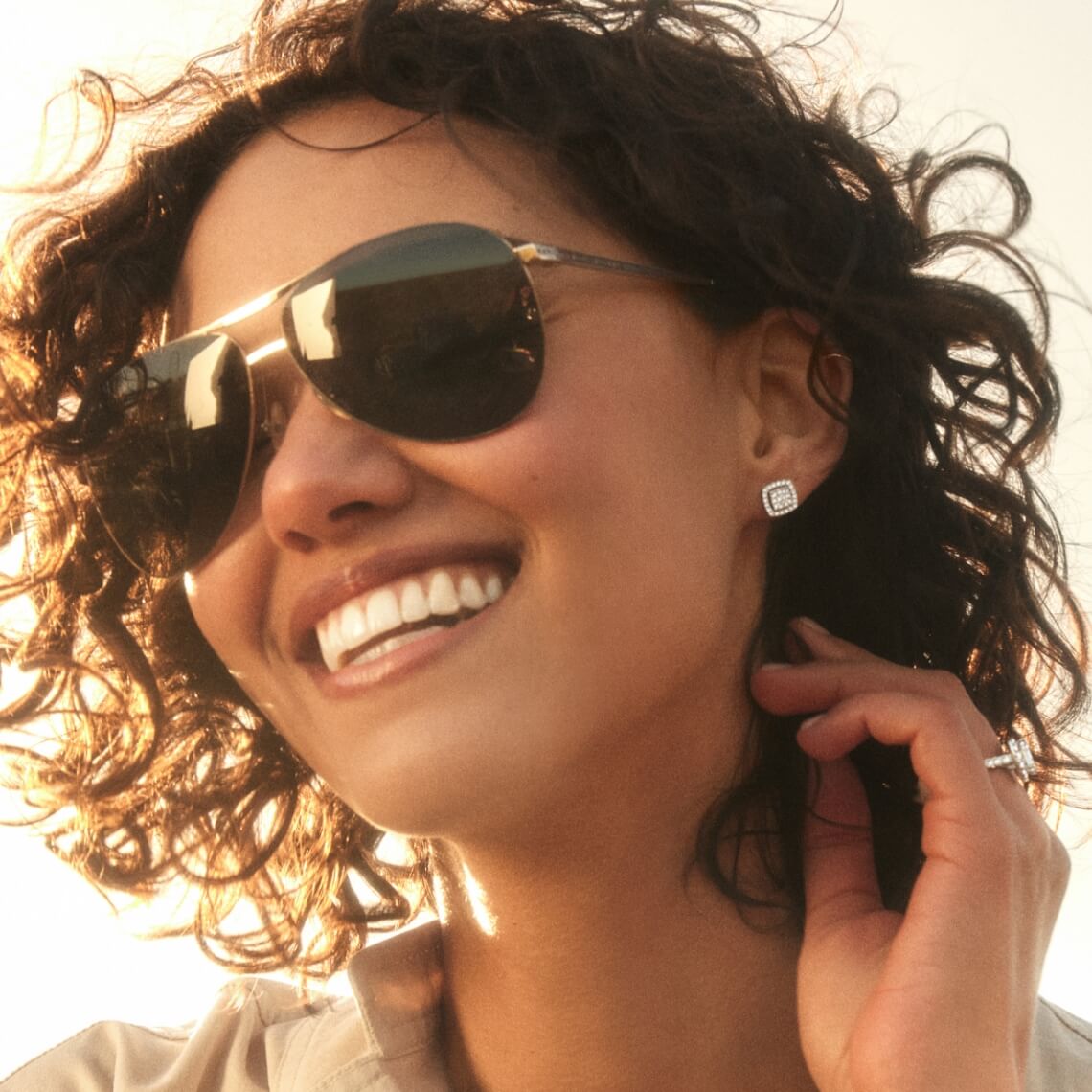 Image of smiling woman wearing sunglasses and diamond jewelry