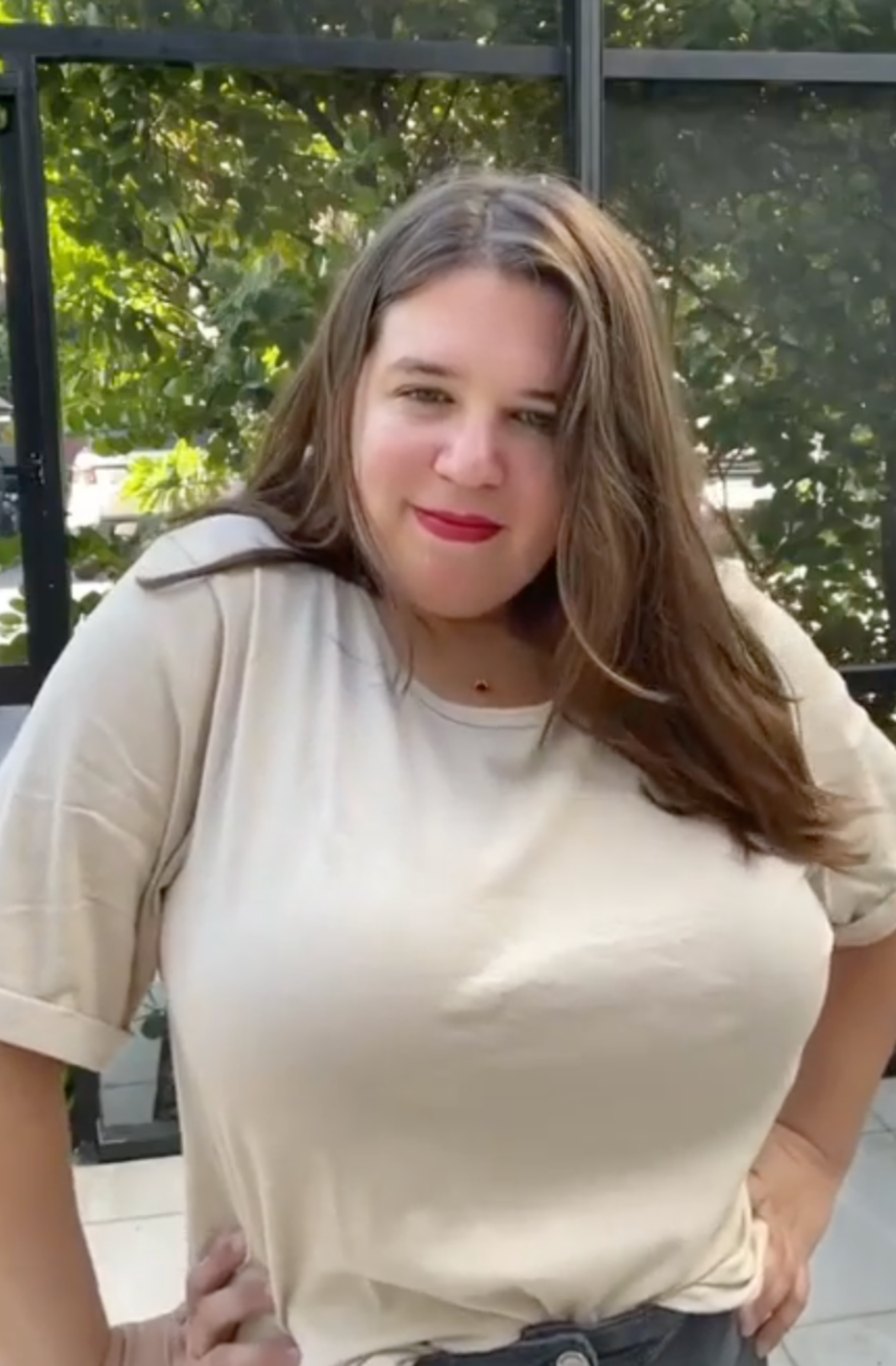 Woman with a fuller bust wearing a beige tshirt and red lipstick