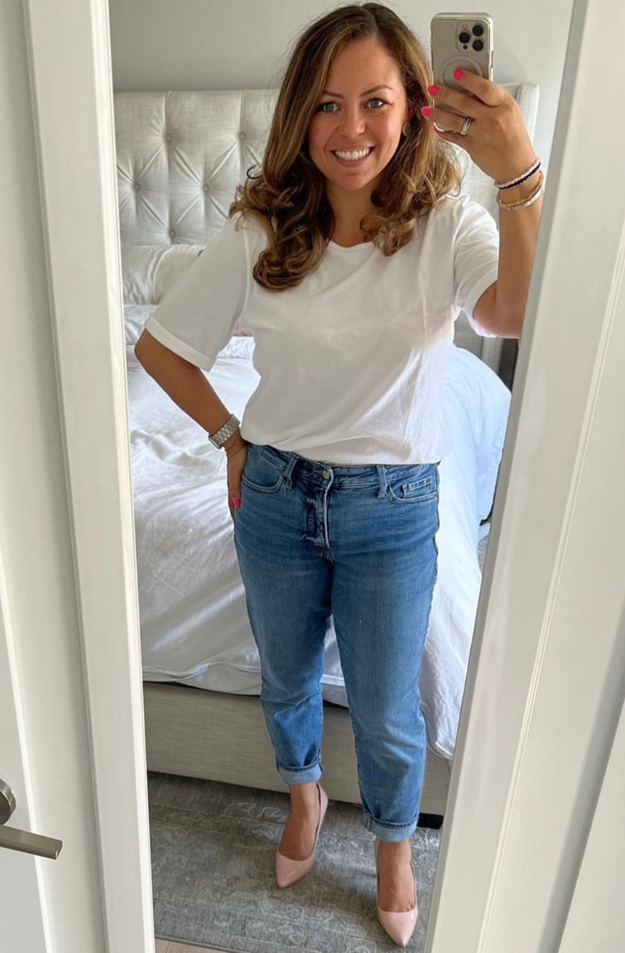 Woman taking a mirror selfie wearing a white tshirt and blue jeans