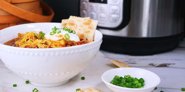 photo of a crockpot with a bowl of food next to it