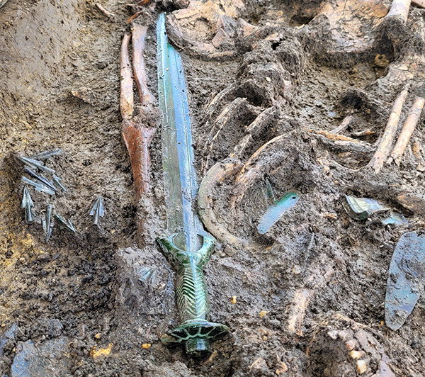 The Nördlingen Bronze age sword shown in situ partly buried in the soil alongside bone remains