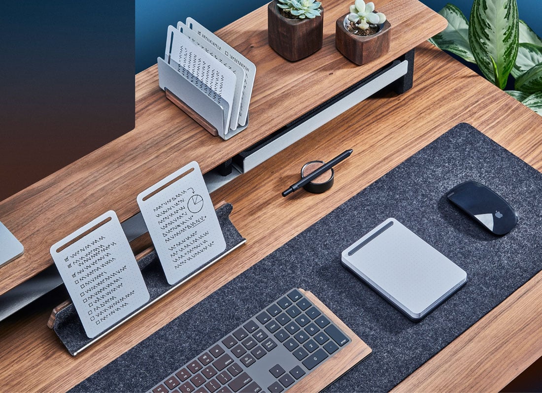 The walnut note-taking kit on walnut desktop with matching wool desk pad.
