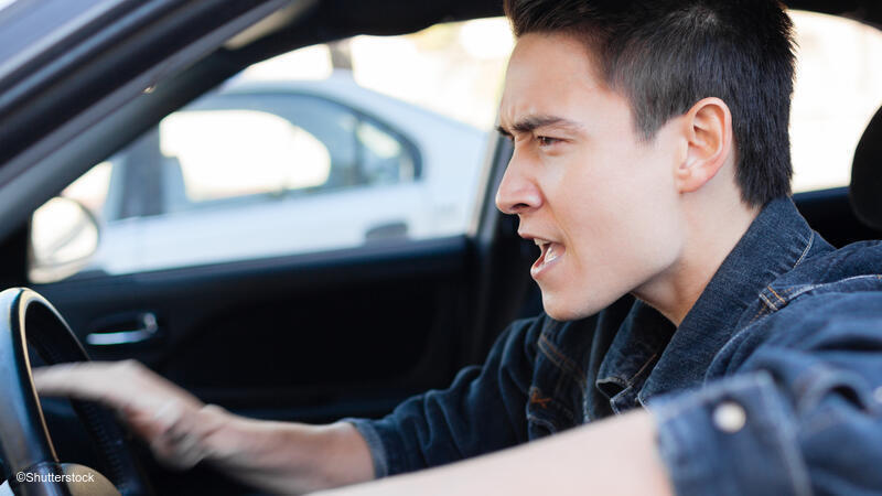 Man appearing angry while driving a car.