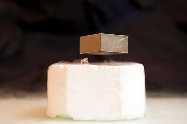 A metal cube is floating above a superconducting magnet cooled by liquid nitrogen.